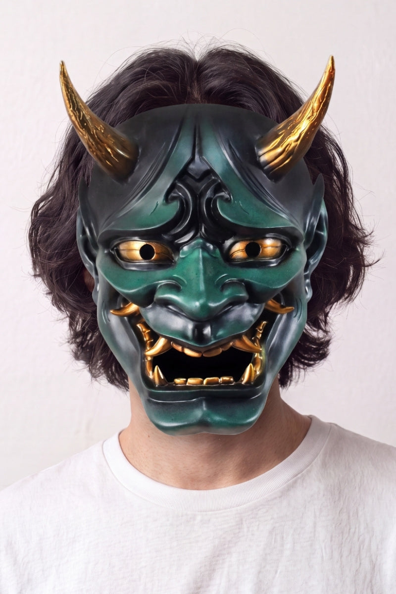 Masque hannya vert porté par un mannequin sur fond clair — démon vert aux cornes dorées, yeux exorbités et mâchoire ouverte sur des crocs