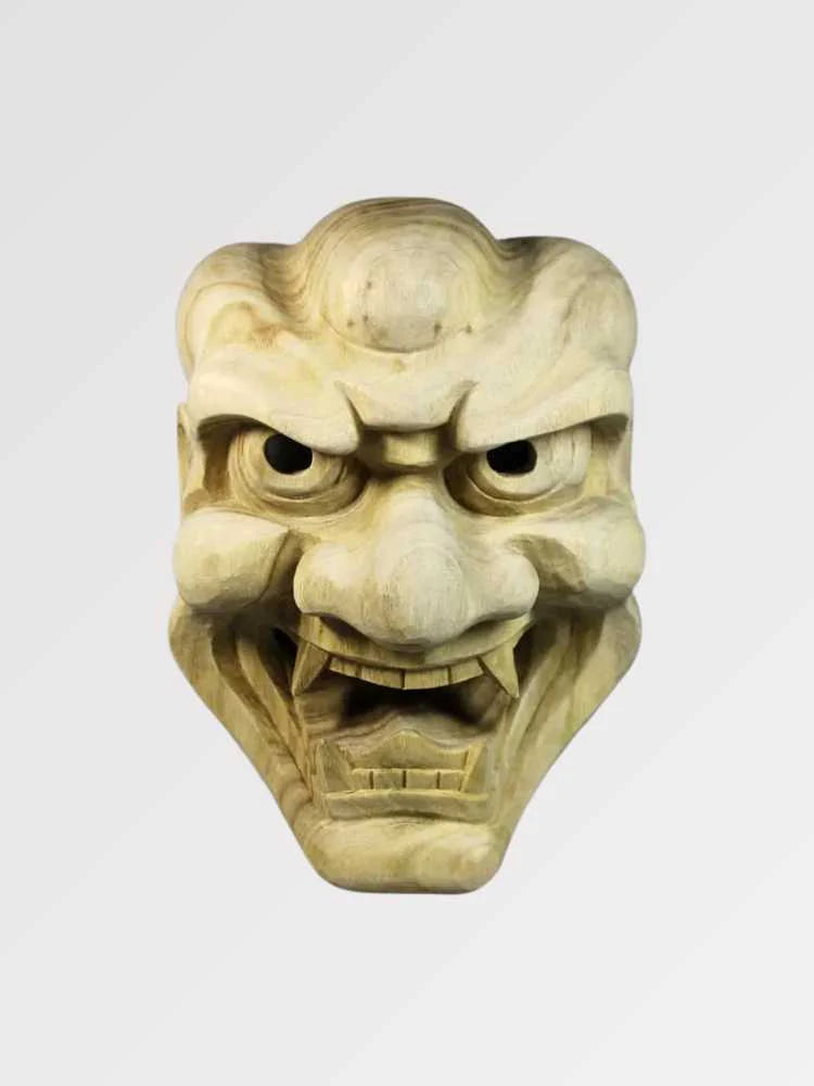 Masque oni en bois sculpté présenté de face sur fond gris uni — démon aux sourcils broussailleux et aux crocs saillants, bois clair veiné