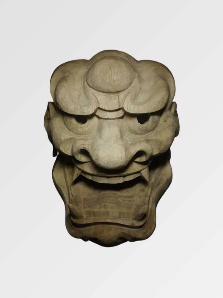Masque shishi présenté de face sur fond gris uni — lion gardien sculpté à la crinière stylisée, mufle large et bouche ouverte