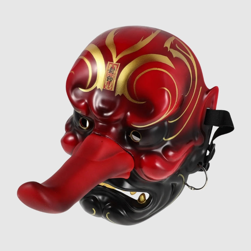Masque tengu rouge vu de trois quarts arrière — long nez proéminent, sourcils en volutes dorées et crocs blancs, intérieur creux visible