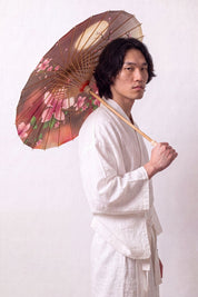 Ombrelle japonaise 'Chisana' ouverte et tenue par un mannequin en kimono blanc — petite toile en dégradé brun et rose à fleurs de cerisier