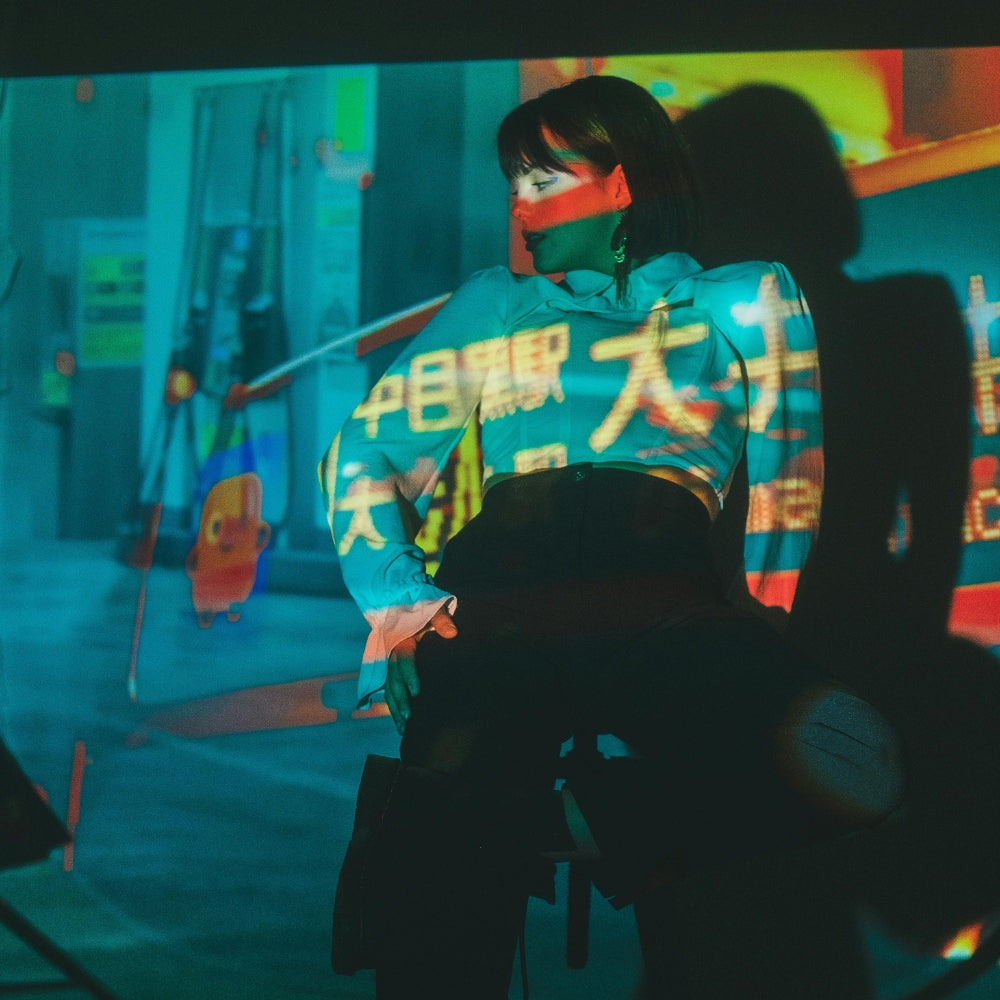 Femme portant un vêtement streetwear inspiré de la mode japonaise, sous des projections de néons à Tokyo – univers Japanstreet