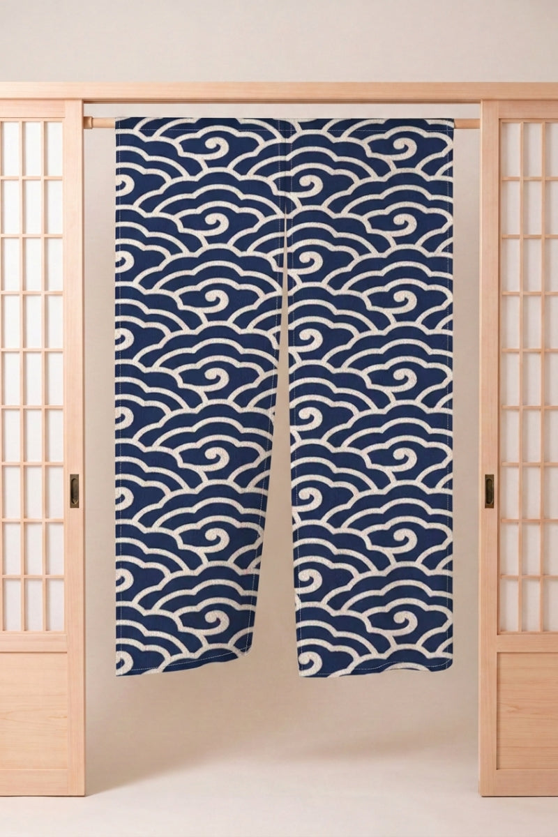 Noren japonais 'Kizuna' suspendu dans l'encadrement d'une porte en bois clair — volutes de nuages blanches sur fond bleu nuit uni, dessin large et régulier