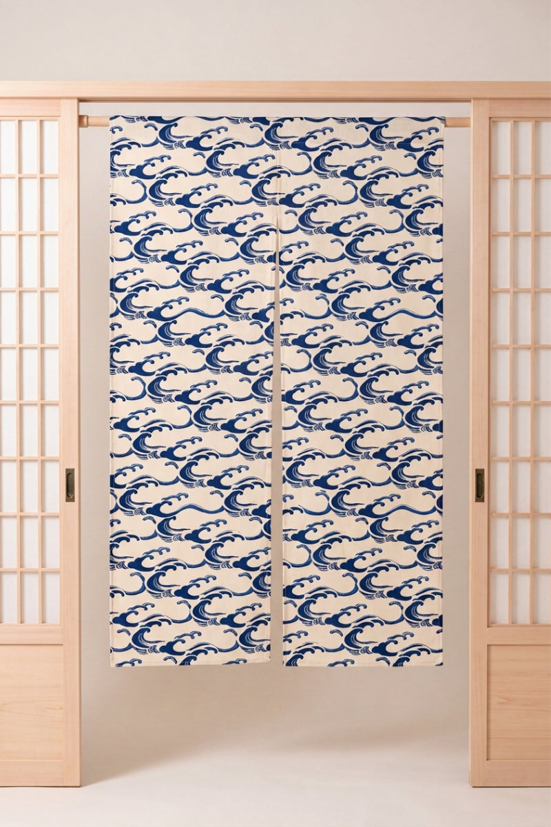 Noren japonais 'Umikaze' suspendu à une porte en bois clair — vagues bleu marine finement dessinées sur fond crème, motif dense couvrant les deux pans
