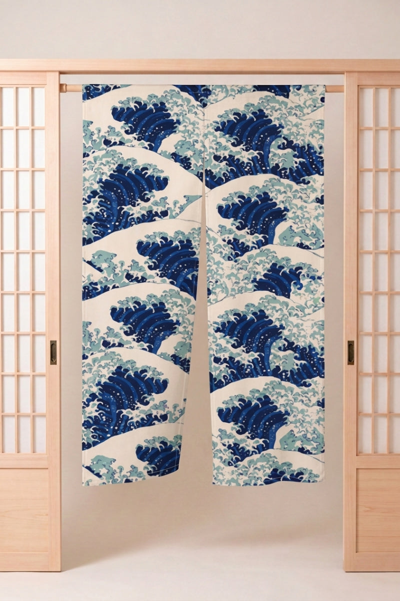 Noren japonais 'Kanagawa Wave' suspendu dans l'encadrement d'une porte en bois clair — grandes vagues d'Hokusai répétées en bleu et blanc sur fond crème