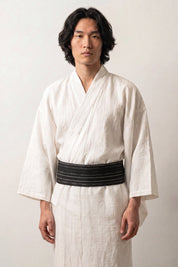 Ceinture obi 'Nahako' portée à la taille sur un kimono blanc par un mannequin homme — noir traversé de rayures blanches fines et espacées