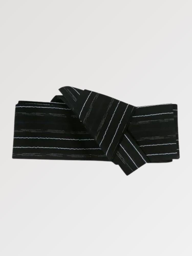 Ceinture obi 'Nahako' pliée à plat sur fond gris, extrémités repliées l'une sur l'autre — noir traversé de rayures blanches fines et espacées