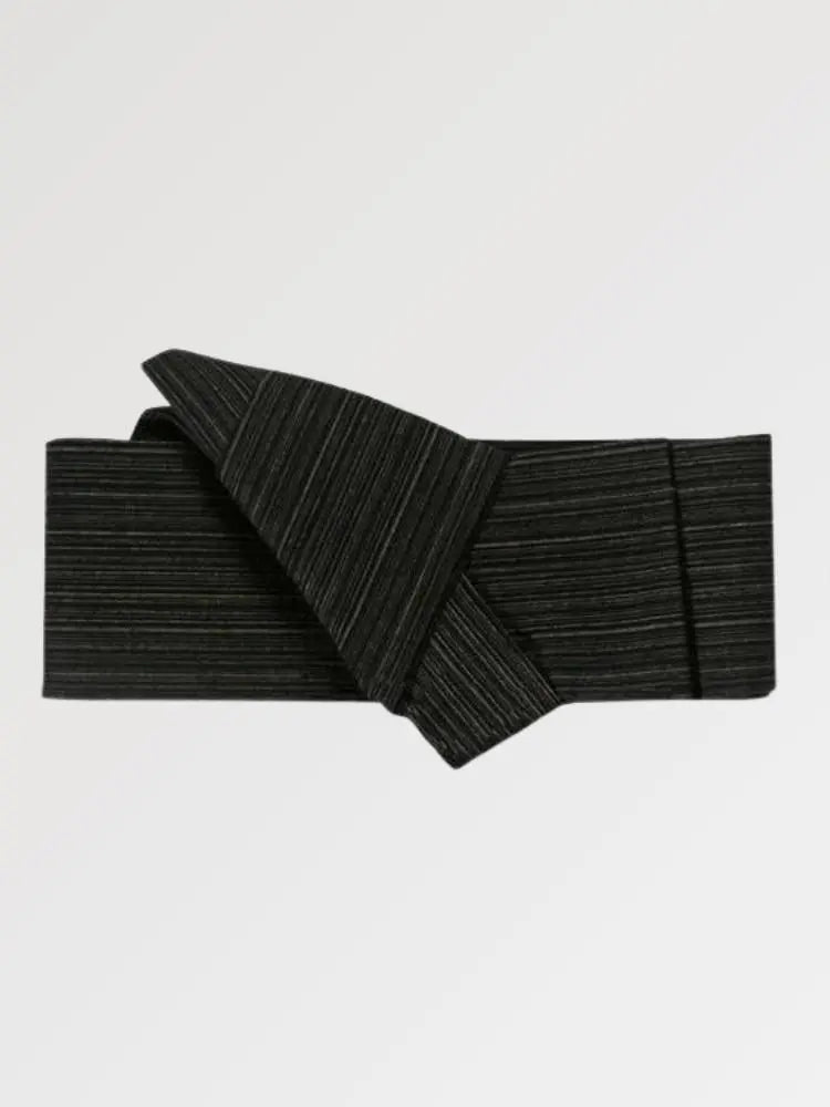 Ceinture obi 'Niigata' pliée à plat sur fond gris, extrémités repliées l'une sur l'autre — noir mat à trame horizontale marquée, sans motif