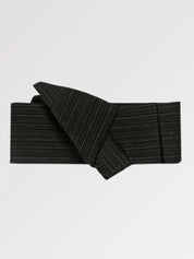 Ceinture obi 'Niigata' pliée à plat sur fond gris, extrémités repliées l'une sur l'autre — noir mat à trame horizontale marquée, sans motif