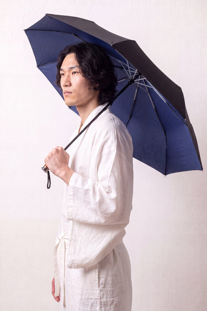 Parapluie japonais 'Komori' ouvert et tenu par un mannequin en kimono blanc — parapluie pliant bleu marine uni à doublure noire anti-UV