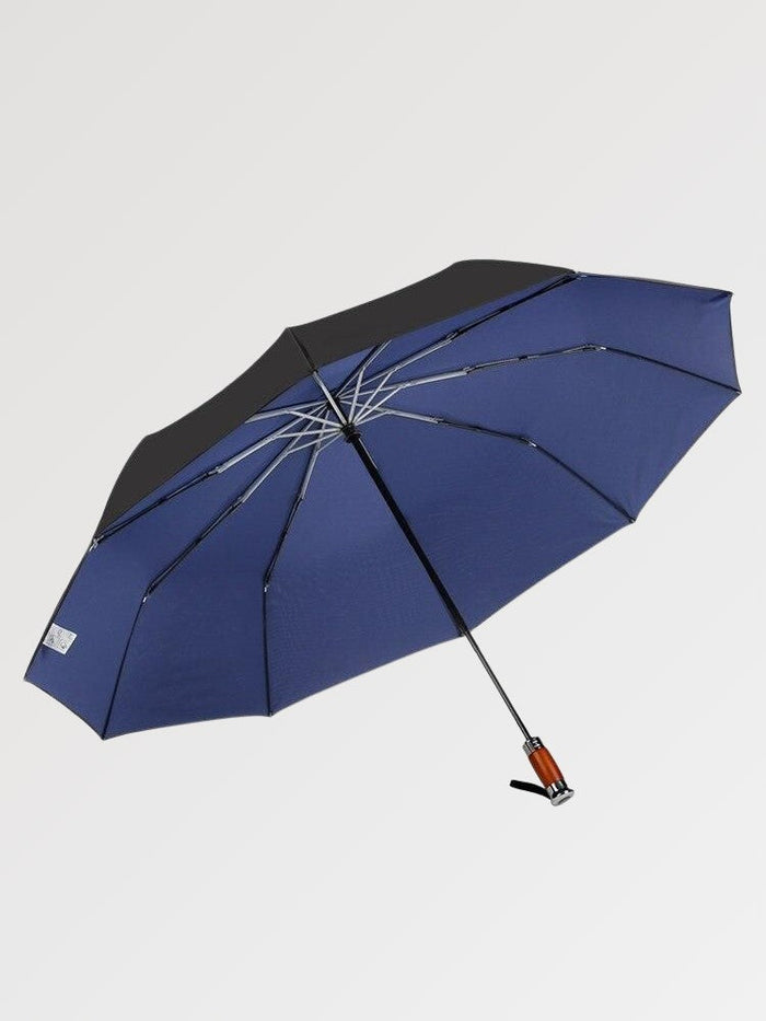 Parapluie japonais 'Komori' ouvert et posé de trois quarts — parapluie pliant bleu marine uni à doublure noire anti-UV, poignée droite et pointe métallique