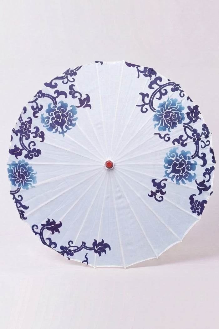 Ombrelle japonaise 'Shiroi' vue de dessus, ouverte à plat — toile blanche à motif floral bleu en couronne, baleines rayonnant depuis le moyeu