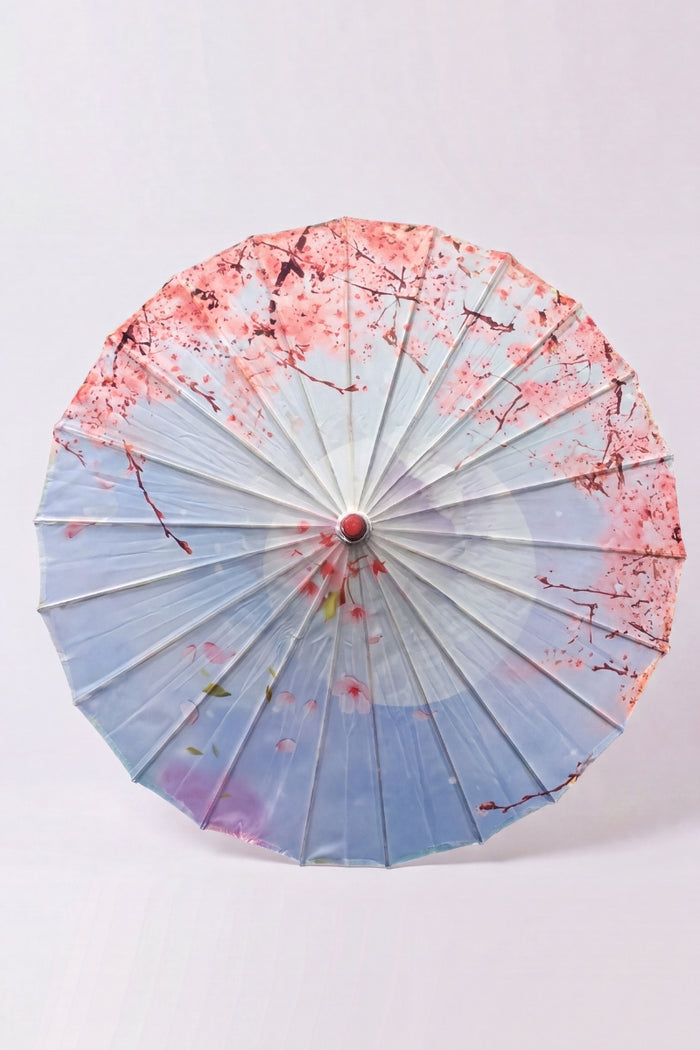 Ombrelle japonaise 'Kekkon' vue de dessus, ouverte à plat — toile bleu clair et rose à nuages stylisés et fleurs, baleines rayonnant depuis le moyeu