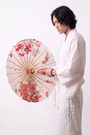 Ombrelle japonaise 'Blossom' ouverte et tenue par un mannequin en kimono blanc — toile blanche à branches de cerisier roses courant vers le centre