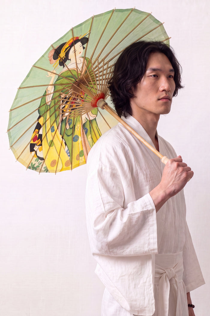 Ombrelle japonaise 'Kimiko' ouverte et tenue par un mannequin en kimono blanc — toile vert olive et jaune à figures de femmes en kimono