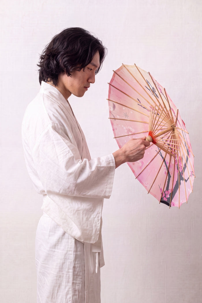 Ombrelle japonaise 'Sakura Fleuri' vue de dessus, ouverte à plat — toile rose dégradée à branche sombre et fleurs de cerisier