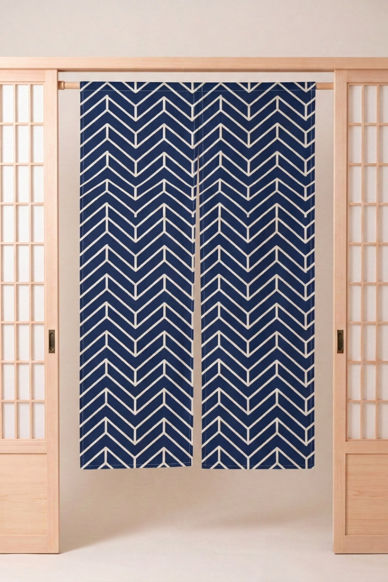 Noren japonais 'Mizu' suspendu dans l'encadrement d'une porte en bois clair — chevrons bleu marine alignés verticalement sur fond écru, motif graphique répété