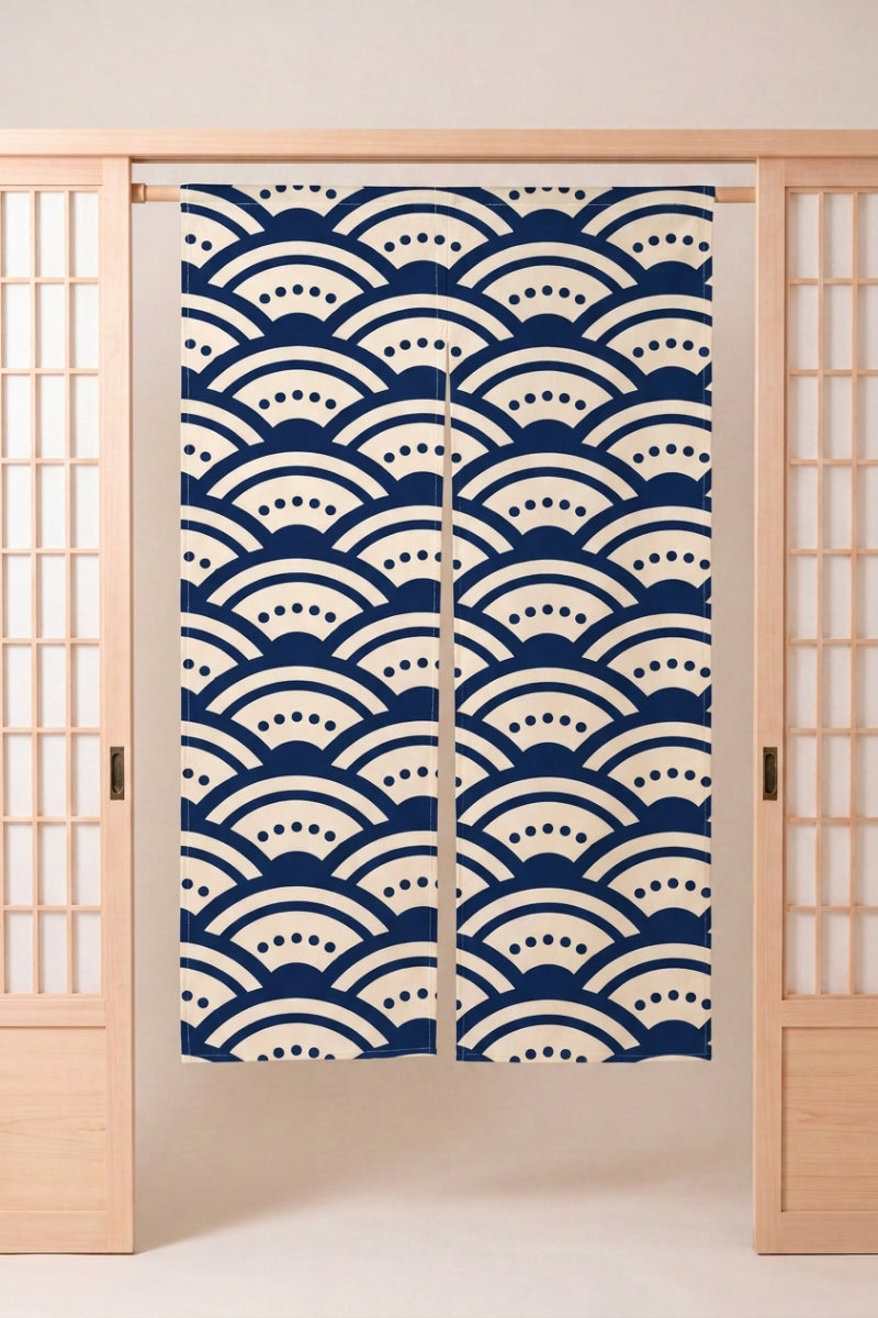 Noren japonais 'Heiwa' suspendu dans l'encadrement d'une porte en bois clair — arcs seigaiha bleu marine ponctués de pointillés blancs sur fond clair
