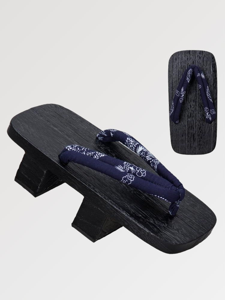 Paire de geta 'Okimari' vue de trois quarts — socle en bois noirci à deux dents, lanière bleu nuit à motif floral blanc, dessous visible