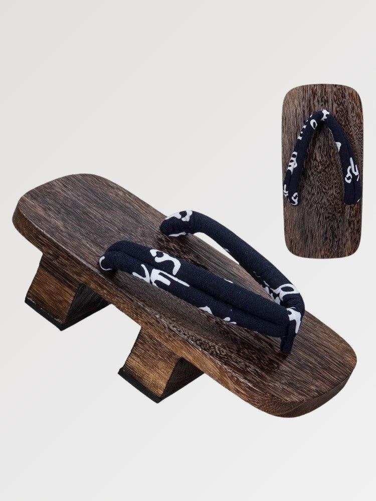 Paire de geta 'Kurashiki' vue de trois quarts — socle en bois foncé à deux dents, lanière bleu nuit à motif blanc, dessous visible