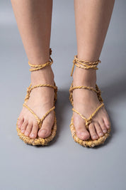 Sandales waraji portées pieds nus, vue de face : semelles en paille tressée et cordes croisées sur le cou-de-pied