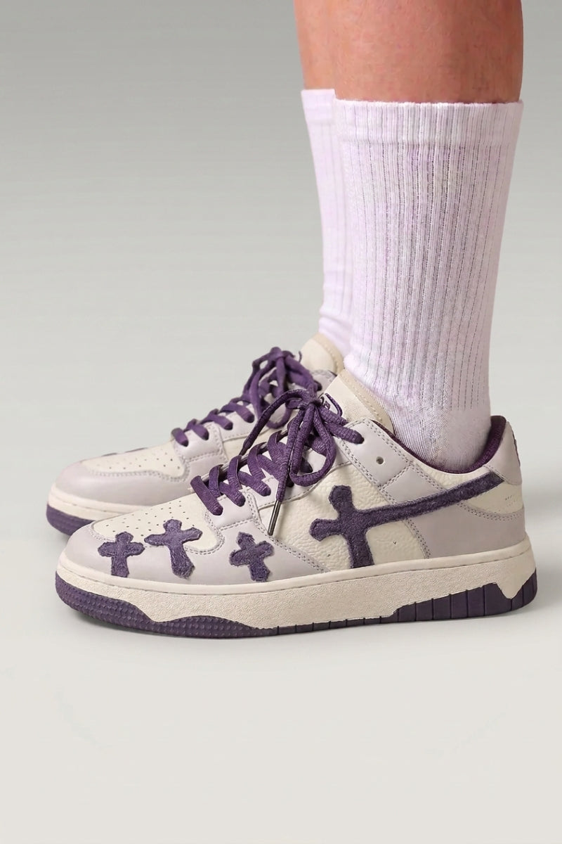 Baskets basses 'Shiro' coloris violet — croix embossées sur les flancs, lacets épais assortis, portées avec chaussettes blanches sur fond studio gris