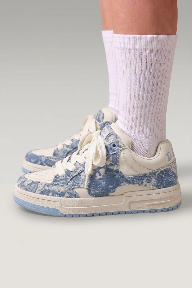 Baskets basses 'Yuki' coloris bleu — toile unie sans surpiqûre apparente, semelle plate contrastée, portées avec chaussettes blanches sur fond studio gris