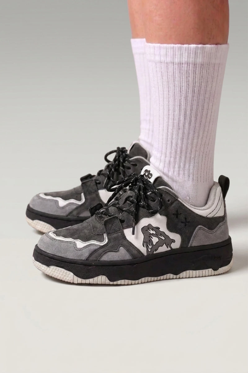 Baskets basses 'Kage' coloris gris — imprimé camouflage gris et noir, laçage fin, semelle discrète, portées avec chaussettes blanches sur fond studio gris