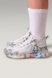Baskets chunky 'Kariya' coloris blanc — imprimé tribal intégral, semelle translucide à confettis, portées avec chaussettes blanches sur fond studio gris
