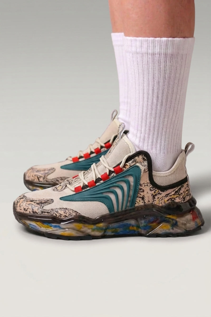 Baskets chunky 'Kariya' coloris gris — imprimé tribal intégral, semelle translucide à confettis, portées avec chaussettes blanches sur fond studio gris