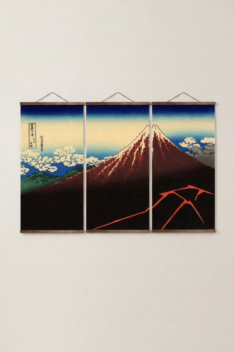 Triptyque japonais 'Fuji Hakuro' accroché à un mur beige — mont Fuji rouge sous l'orage, éclairs à sa base, sur trois panneaux