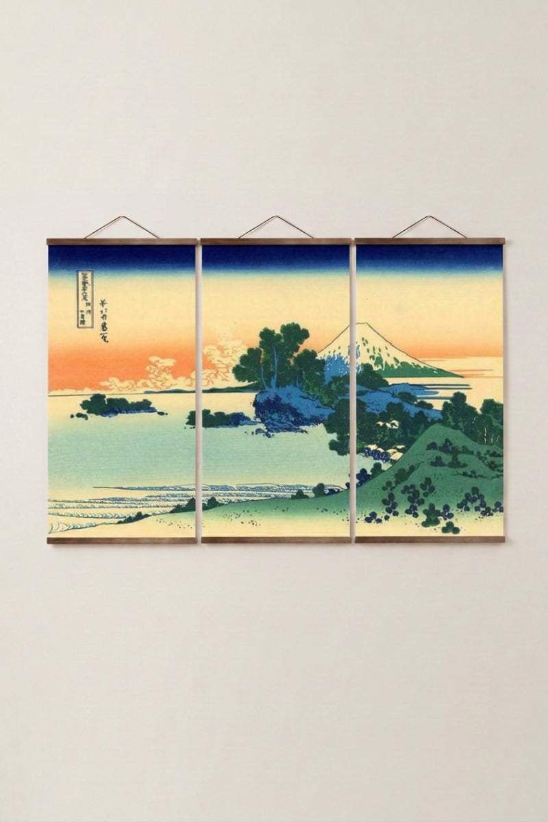 Triptyque japonais 'Aka Machi' accroché à un mur beige — mont Fuji au couchant derrière une eau turquoise et des pins, trois panneaux