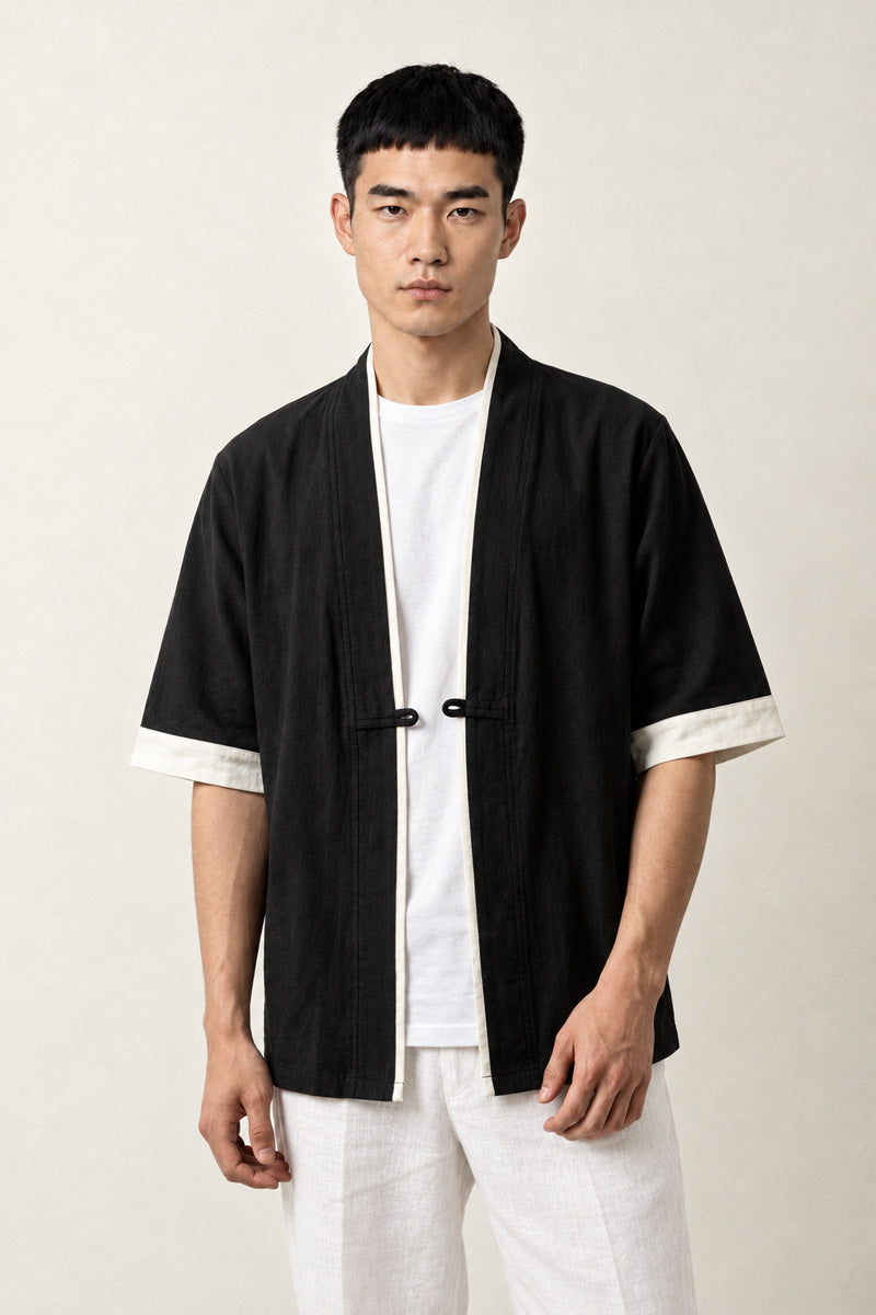 Veste kimono homme Hideki noire coton liseré blanc manches courtes col en V, porté par un homme, vue de face.