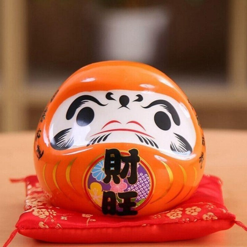 Daruma orange à kanji 財旺 zaiō (richesse florissante) pour prospérité commerciale, tirelire peinte main — vue de détail visage