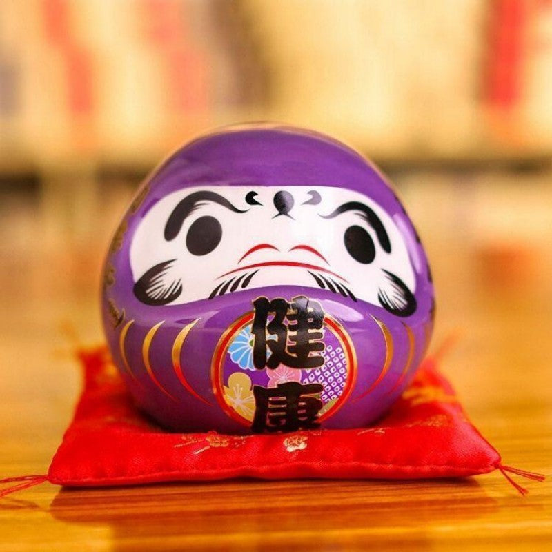 Daruma violet impérial à kanji 健康 kenkō (santé) pour vœu de longévité, tirelire porcelaine peinte main — vue de détail visage