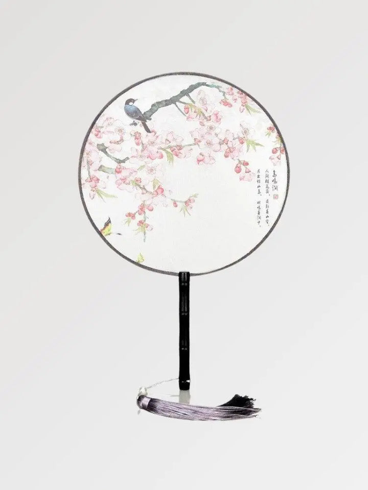 Un éventail japonais rond au tissu blanc dans un motif de fleurs et d'oiseaux