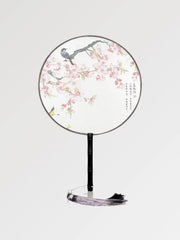 Un éventail japonais rond au tissu blanc dans un motif de fleurs et d'oiseaux